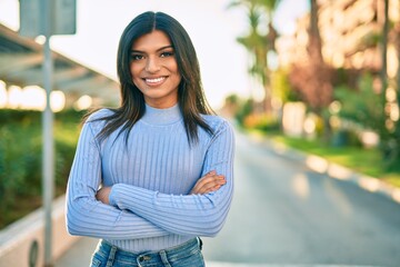 Beautiful hispanic woman smiling confient with crossed arms at the city - obrazy, fototapety, plakaty