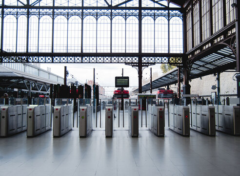 Imagen de los tornos digitales de la entrada al servicio de transporte público de tren con los trenes y andenes de fondo.