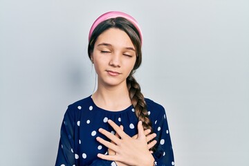 Young brunette girl wearing elegant look smiling with hands on chest with closed eyes and grateful gesture on face. health concept.