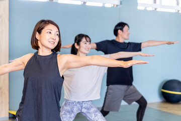 Naklejka premium スポーツジムでヨガをする男女（戦士のポーズ） 