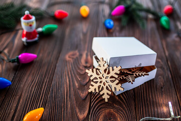 Gift box with hand-carved wooden snowflakes. Christmas sale, discounts template with christmas decorations, garland with colorful light bulbs, clockwork santa claus and fir branches