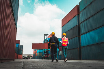 Industrial worker works with co-worker at overseas shipping container yard . Logistics supply chain...