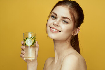 woman with cucumber drink vitamins body care yellow background