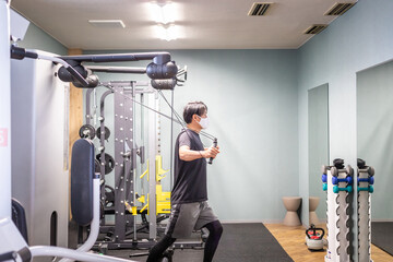 スポーツジムでケーブルマシンを使う男性
