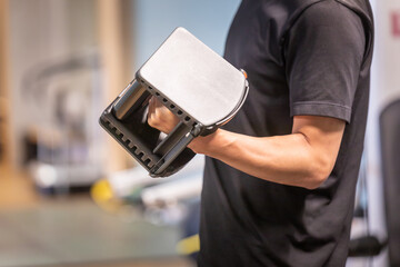 スポーツジムでブロックダンベルを使う男性（顔なし）
