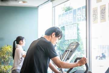 スポーツジムで運動する男性（男女・笑顔）
