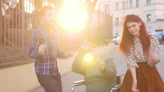 solidarity, affection -  slow motion on young woman and young man involving their friend with paraplegia in a wild dance