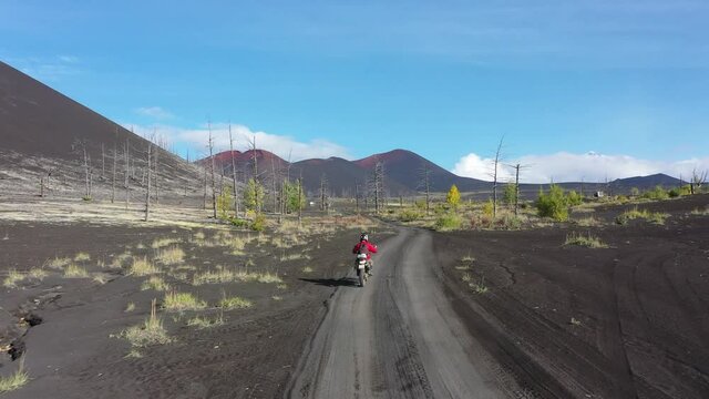 Motorcyclist in dead forest, post-apocalyptic landscape, Volcanic slag, the territory of the active Tolbachik volcano