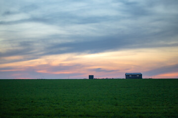 Fototapeta premium Coucher du soleil coloré sur une maison isolée dans un champ