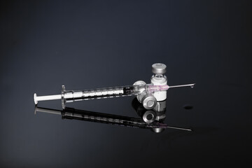 Syringe with vials and Needle on dark background