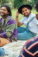 Malaysian Indian men in a group against a cloth backdrop in a park surrounded by trees, talking,...