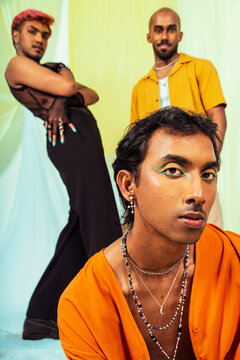 A group of Malaysian Indian men wearing make up posed in a studio setting against a cloth background