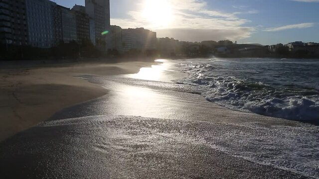 Sunset sunlight reflecting on the wave-wet beach sand