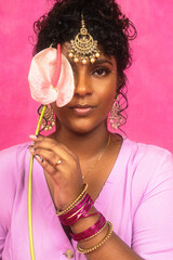 Malaysian Indian individual laughing and posing in a studio setting with a pink background