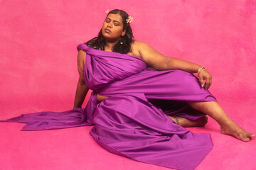 Malaysian Indian individual laughing and posing in a studio setting with a pink background