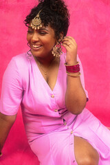 Malaysian Indian individual laughing and posing in a studio setting with a pink background