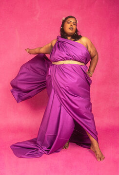 Malaysian Indian individual posed against pink background, styled in pionk and white, studio setting