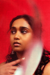 Malaysian Indian individual dressed in red clothing, against a red background, posing and laughing
