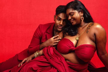 Fotobehang A Malaysian Indian male and female lying next to each other against a red background © Daniel Adams