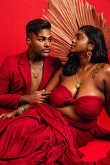 A Malaysian Indian male and female lying next to each other against a red background