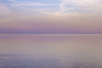 Obraz premium Beautiful sunset on sea, pastel colors and reflections on water, calm nature landscape with colorful clouds