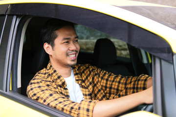 Adult Asian man smiling happy while driving a car - obrazy, fototapety, plakaty