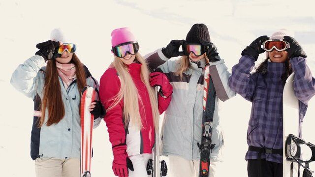 Women snowboarders and skiers on mountain slope talking and relaxing after slide
