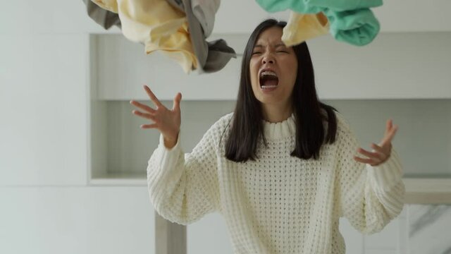 Aggressive asian woman throws her underwear in the air. The concept of home cleaning and Laundry.