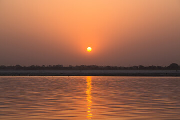 インド　ヴァラナシの早朝のガンジス川と朝日でオレンジ色に染まった空