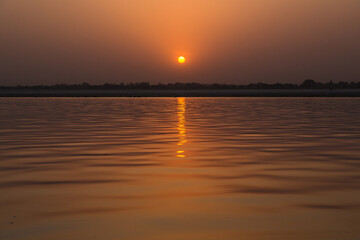 インド　ヴァラナシの早朝のガンジス川と朝日でオレンジ色に染まった空