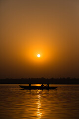 インド　ヴァラナシの早朝のガンジス川に浮かぶボートと朝日でオレンジ色に染まった空
