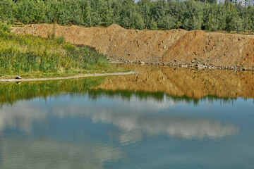 A pit filled with water near the city.Reflection of the sky in the water