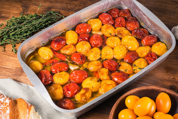 Tomato confit in a baking sheet, close-up on a table with ingredients for cooking