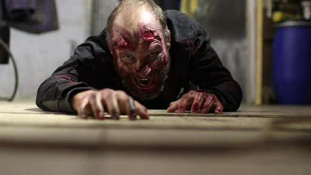 Zombie male with makeup for halloween concept creep on floor