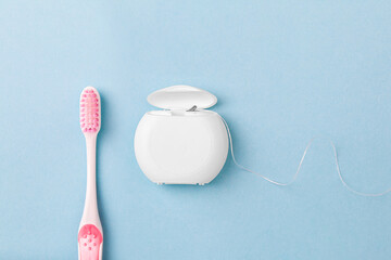 dental floss and toothbrush on blue background. Care of teeth health. Everyday routine teeth...