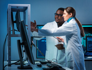 Group of microelectronic engineers discussing in a modern microprocessor manufacture lab. Workplace...