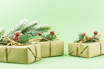 three festive New Year's gifts packed in craft paper with decoration from branches of spruce and berries. close angle.
