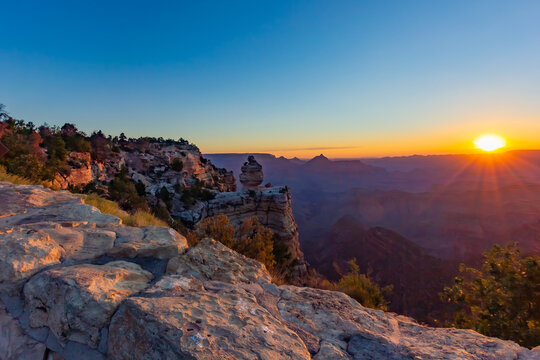Sunrise at Grand Canyon, Colorado, USA, photographed from a viewpoint in late summer. The golden hue of the rising sun is reflected on the different layers of rocks formed over millions of years.  