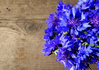 Cornflower flowers. Blue flowers on a background of a wooden surface - obrazy, fototapety, plakaty