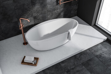 Oval white ceramic bathtub in grey bathroom with copper details. Top view.