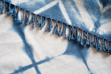 Natural handmade tie dye cloth or fabric shawl in white and blue pattern with tassel or festoon
