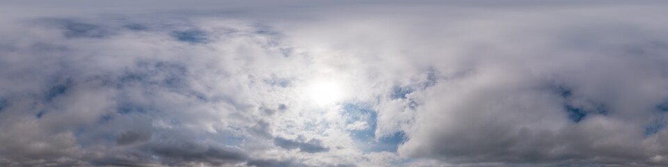 Blue evening sky seamless panorama spherical equirectangular 360 degree view with Cumulus clouds, setting sun. Full zenith for use in 3D graphics, game and aerial drone panoramas as sky replacement.