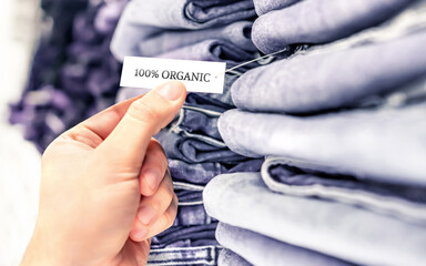 Organic jeans, ethical denim pants. Stack of clothes in store shelf. Label and tag. Sustainable...