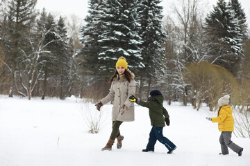 Happy family playing and laughing in winter outdoors in the snow. City park winter day.