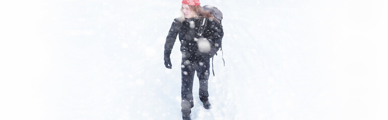 A man travels with a backpack. Winter hike in the forest. Tourist on a walk in the winter in the park.