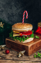 Christmas burger concept, with candy cane and christmas gift box. Dark background, Selective focus