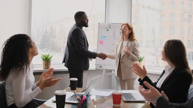 Business partners at negotiation. Multiethnic teams make agreement at briefing meeting. African american male boss shaking hands with caucasian female colleague, sign a contract, collaboration concept