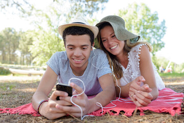 young couple lying down in a park listening to music