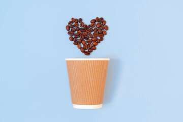 Creative flat lay with paper disposable coffee cup and roasted coffee beans in a form of a heart on pastel blue background. Eco-friendly and zero waste concept