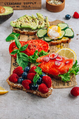 Breakfast Toast Variation with avocado, salmon, egg, cucumber, berries on baking paper